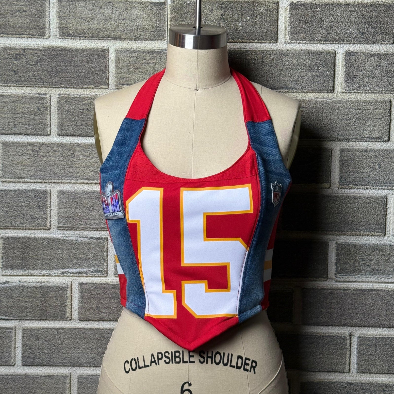 Red Kansas City Chiefs women’s jersey halter corset top with number 15, denim side panels, and Super Bowl patch, displayed on a mannequin.
