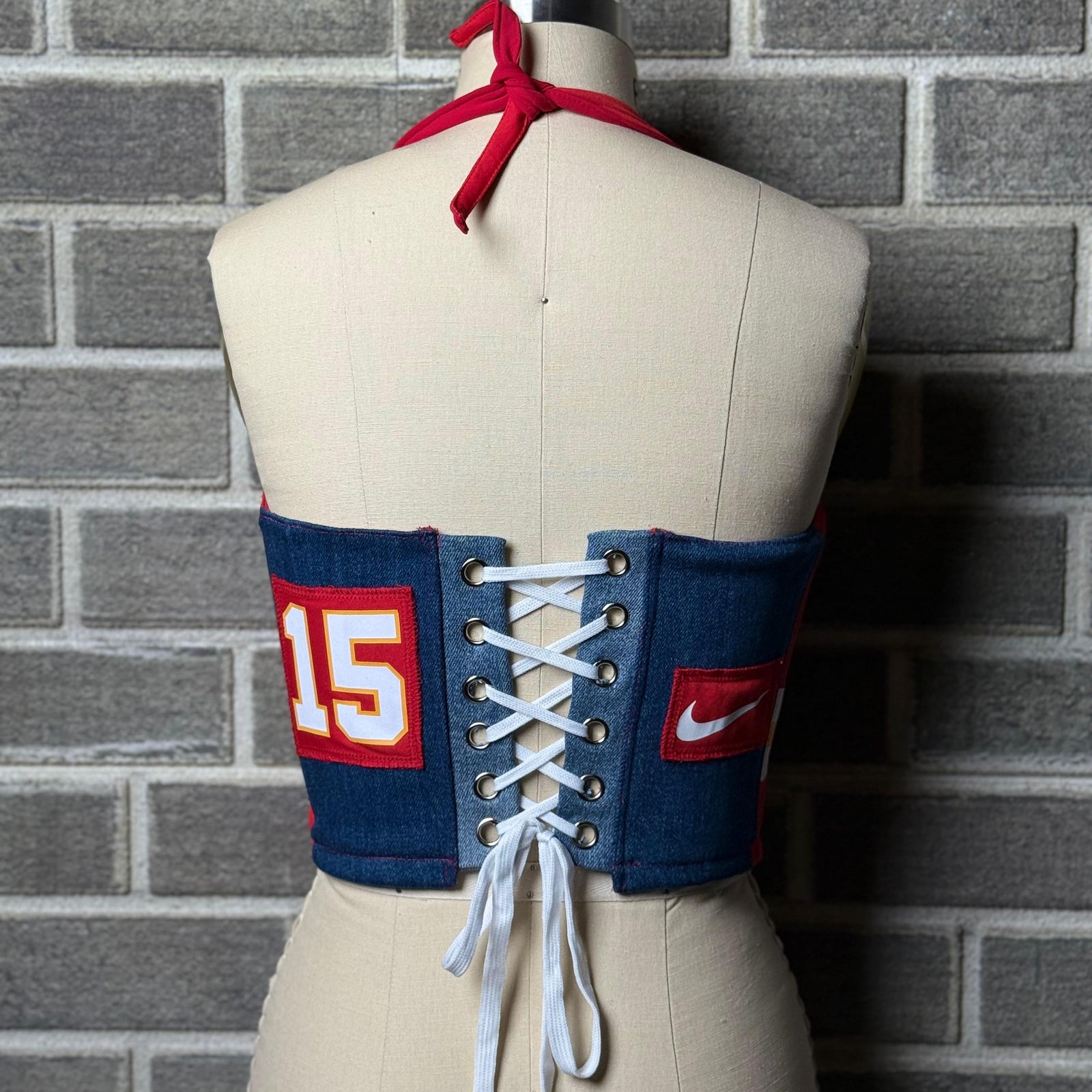 Red Kansas City Chiefs women’s jersey halter corset top with number 15, denim side panels, and Super Bowl patch, displayed on a mannequin.
